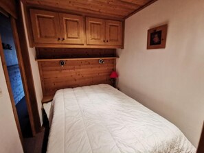 A bedroom with a bed, wooden headboard, and a red lamp. - 10m from ski slopes, 1st floor, view ski slopes, balcony, 32m², Méribel-Mottaret (Méribel - Les Allues)
