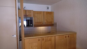 A kitchen with wooden cabinets, a microwave, and a tiled backsplash.