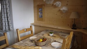 A wooden dining table with a woven basket, plates, and a loaf of bread. - 150m from shops, 5th floor, balcony, ski locker, 40m², Méribel-Mottaret (Méribel - Les Allues)
