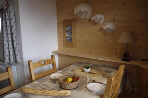A wooden dining table with a woven basket, plates, and a loaf of bread. - 150m from shops, 5th floor, balcony, ski locker, 40m², Méribel-Mottaret (Méribel - Les Allues)
