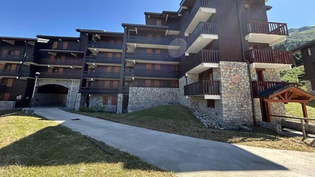 A multi-story hotel with balconies, stone accents, and a clear sky. - 150m from shops, 5th floor, balcony, ski locker, 40m², Méribel-Mottaret (Méribel - Les Allues)
