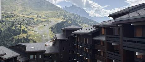 A multi-story hotel with balconies overlooking a mountainous landscape.