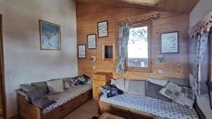 A cozy cabin with two wooden beds, a small table, and a window with curtains. - 150m from shops, 5th floor, balcony, ski locker, 40m², Méribel-Mottaret (Méribel - Les Allues)