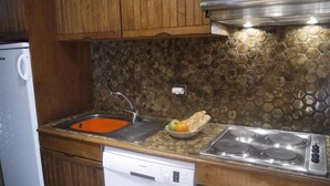 A kitchen with wooden cabinets, a Bosch dishwasher, a sink with a hexagonal tile backsplash, and a stove. - 20m from ski slopes, 8th floor, view mountain, balcony, ski locker, 32m², Méribel-Mottaret (Méribel - Les Allues)