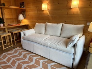 Una stanza accogliente con un divano beige, un tappeto decorato e pareti in legno.