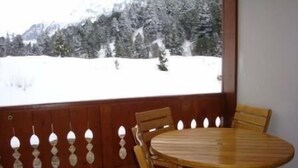 A wooden dining table with chairs in a room with a view of a snowy landscape. - 350m from ski slopes, balcony, tv, 40m², Méribel-Mottaret (Méribel - Les Allues)