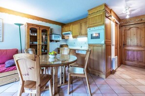A kitchen with wooden cabinets, a round glass table, and chairs. - 350m from ski slopes, balcony, tv, 40m², Méribel-Mottaret (Méribel - Les Allues)