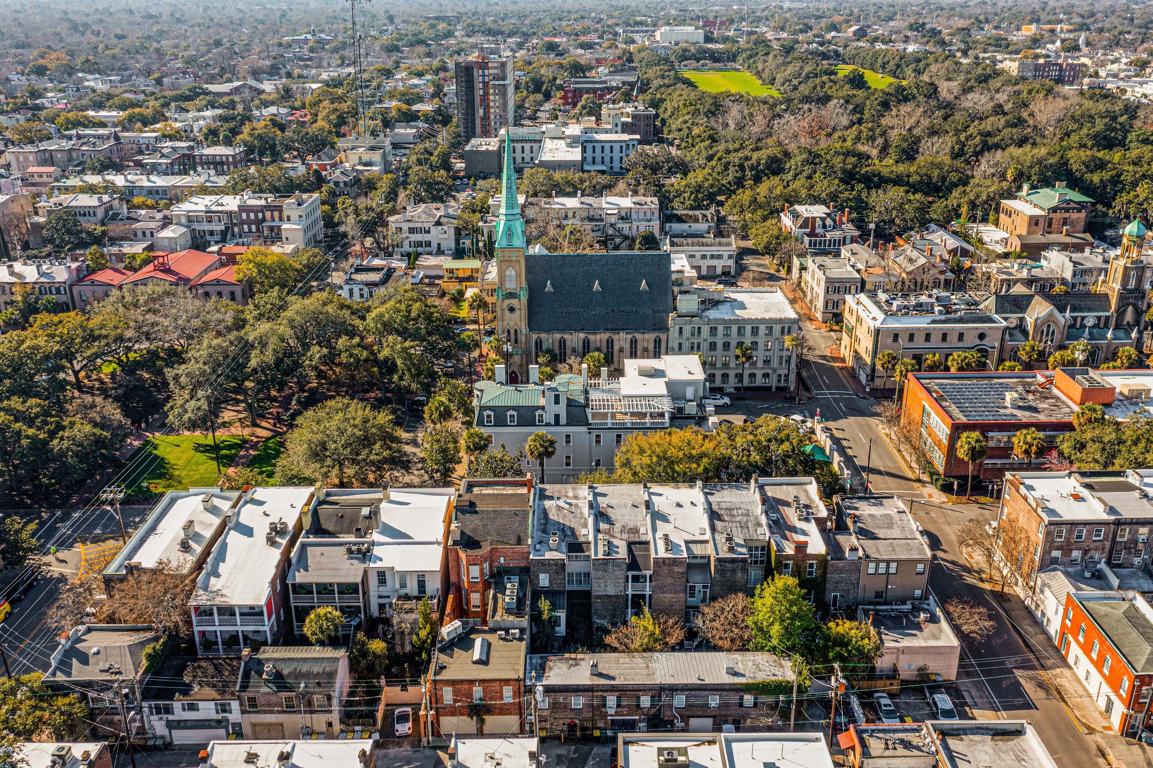 An aerial view of a densely populated urban area with various buildings, including a prominent church with a green spire.
