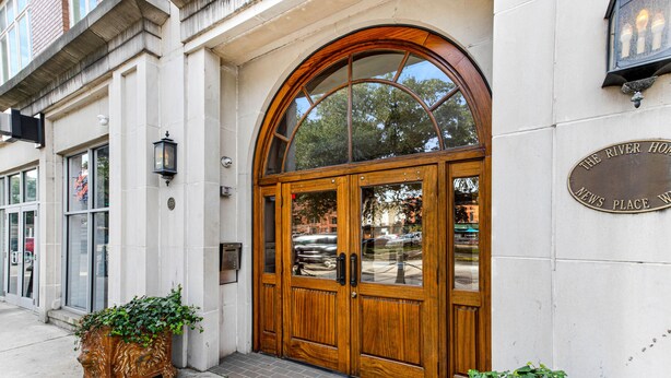Una entrada de edificio con una puerta de madera grande, un ventanal y un letrero que dice "The River House News Place".