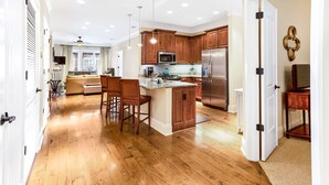Una cocina amplia con suelo de madera, una isla central y electrodomésticos de acero inoxidable.