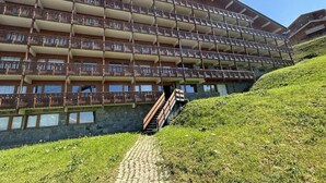 A multi-story hotel with balconies, a stone foundation, and a paved pathway leading to the entrance. - 270m from shops, 3rd floor, balcony, tv, 35m², Méribel-Mottaret (Méribel - Les Allues)