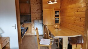 A compact kitchen with wooden cabinets, a dining table, and chairs. - 270m from shops, 3rd floor, balcony, tv, 35m², Méribel-Mottaret (Méribel - Les Allues)