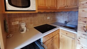 A kitchen with wooden cabinets, a white countertop, a built-in microwave, a coffee maker, and a sink. - 270m from shops, 3rd floor, balcony, tv, 35m², Méribel-Mottaret (Méribel - Les Allues)