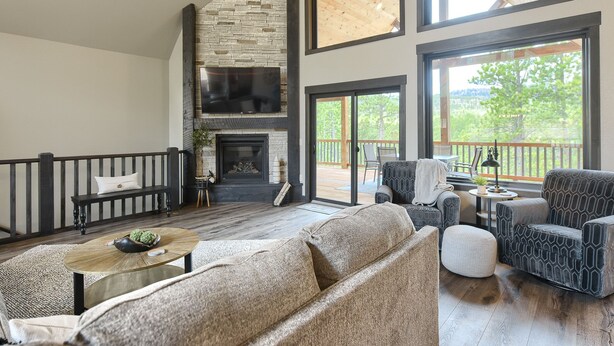 A spacious living room with a stone fireplace, large windows, and a balcony with outdoor furniture. - 4,000 Sq. Ft. New Beautiful Lodge in Powder House and Large Deck w/ View! (Lead)