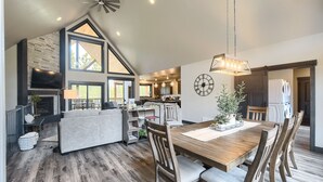 A spacious living area with a fireplace, a dining table, and a kitchen in the background. - 4,000 Sq. Ft. New Beautiful Lodge in Powder House and Large Deck w/ View! (Lead)
