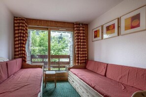 A room with a wooden bench, a small table, and a window with curtains.