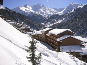 A snow-covered mountain resort with wooden cabins and a ski slope.