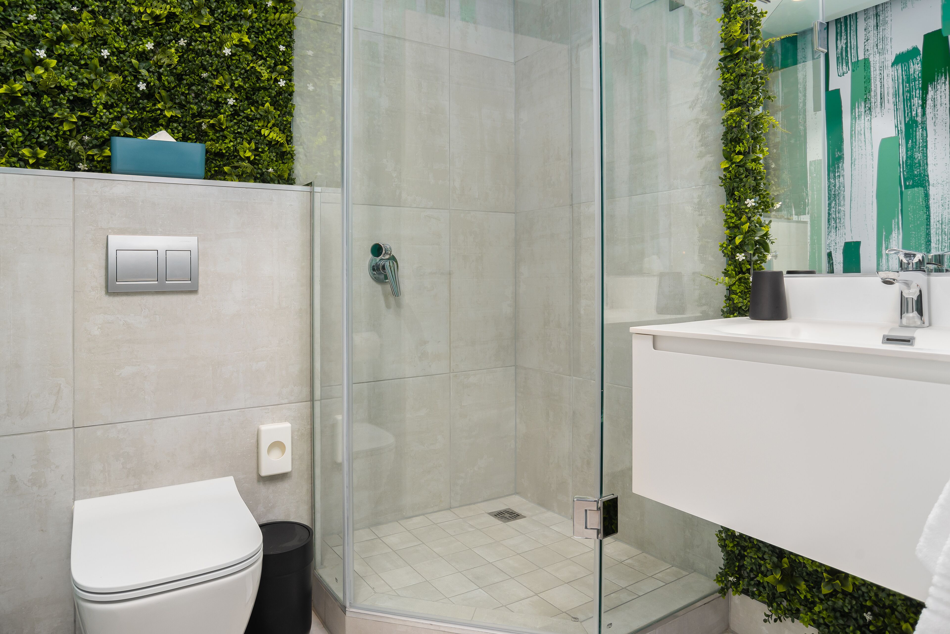 Une salle de bain moderne avec une douche à parois de verre, des toilettes blanches et un lavabo avec un miroir.