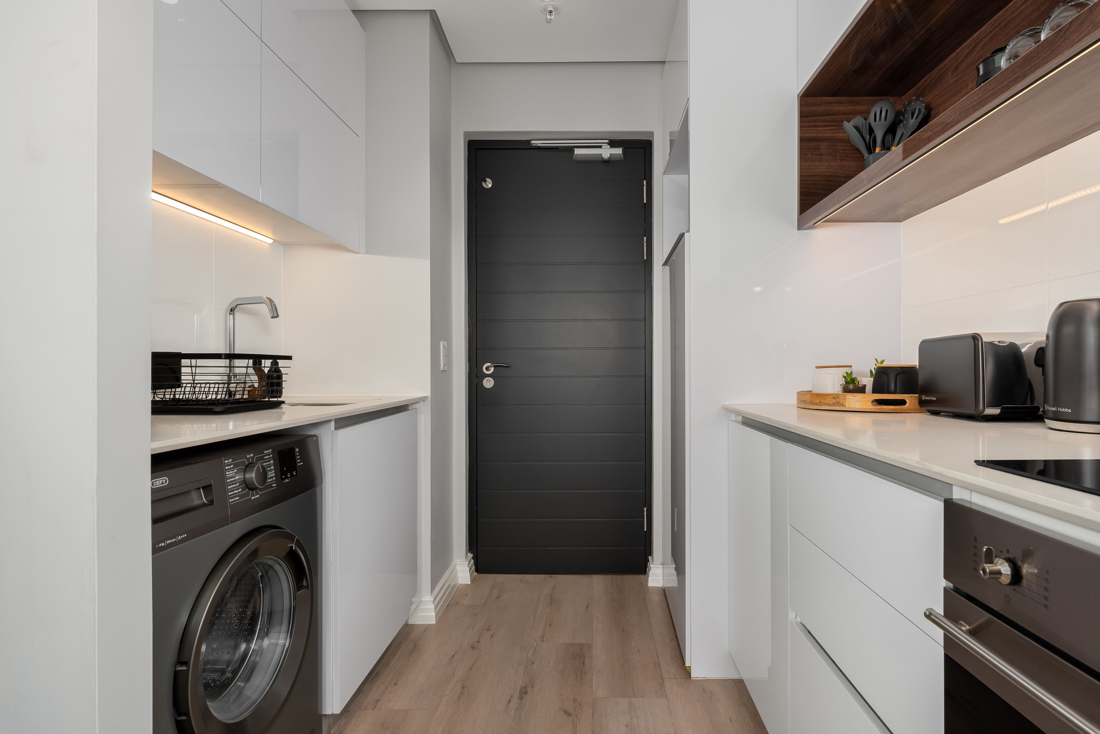 Une cuisine compacte équipée d’un lave-linge, d’un four  à micro-ondes et d’un grille-pain.