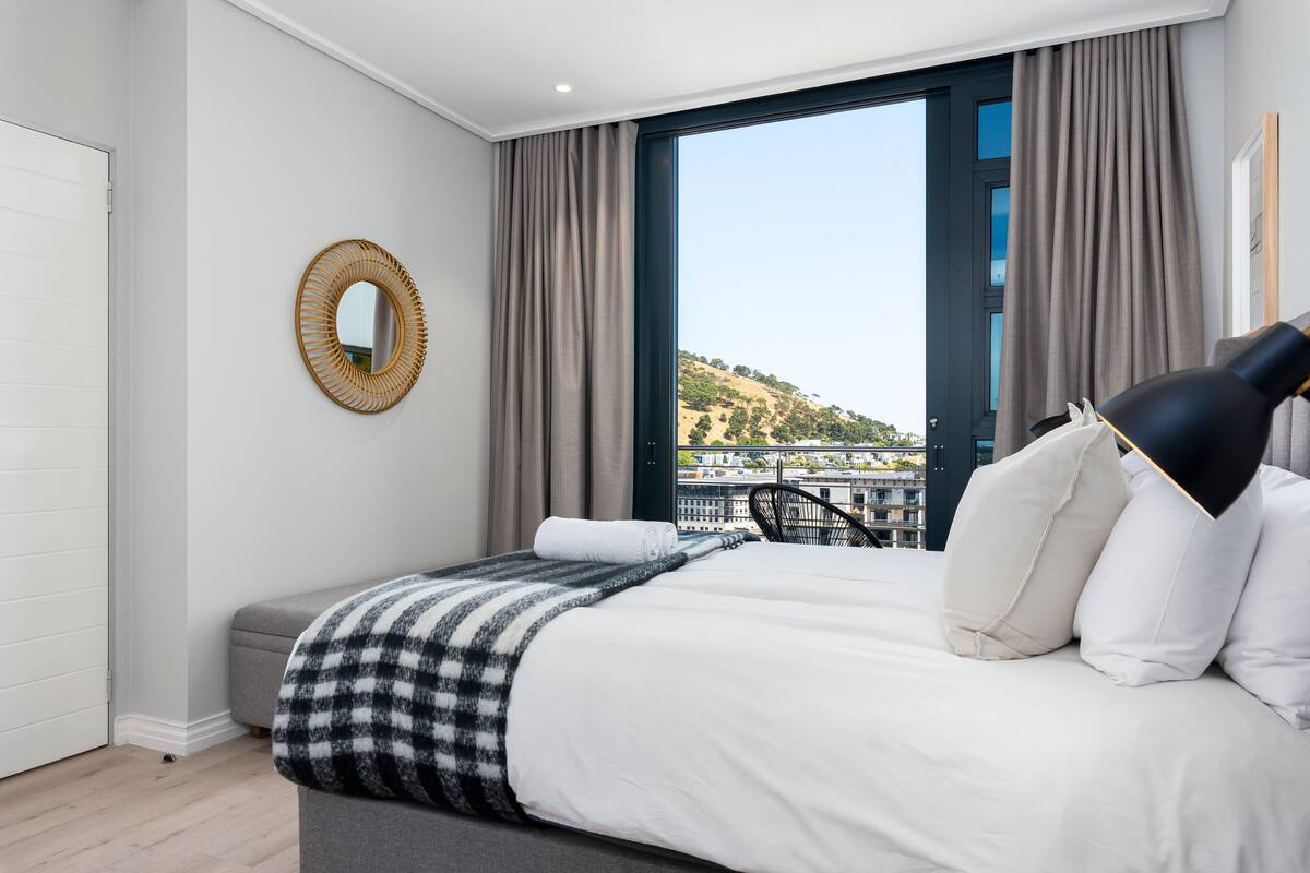 Une chambre moderne avec un grand lit, une vue sur une colline et un balcon avec une chaise.