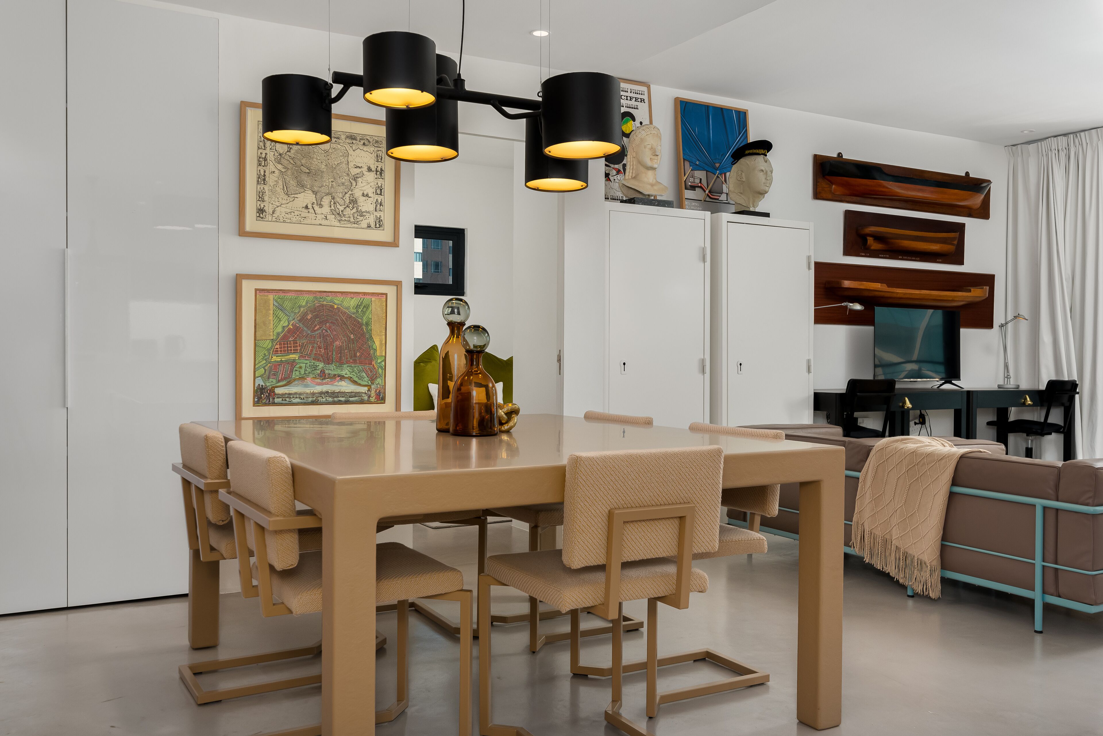 A modern dining area with a wooden table and chairs, a chandelier, and artwork on the walls.
