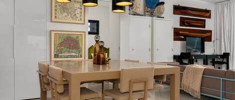 A modern dining area with a wooden table and chairs, a chandelier, and artwork on the walls.