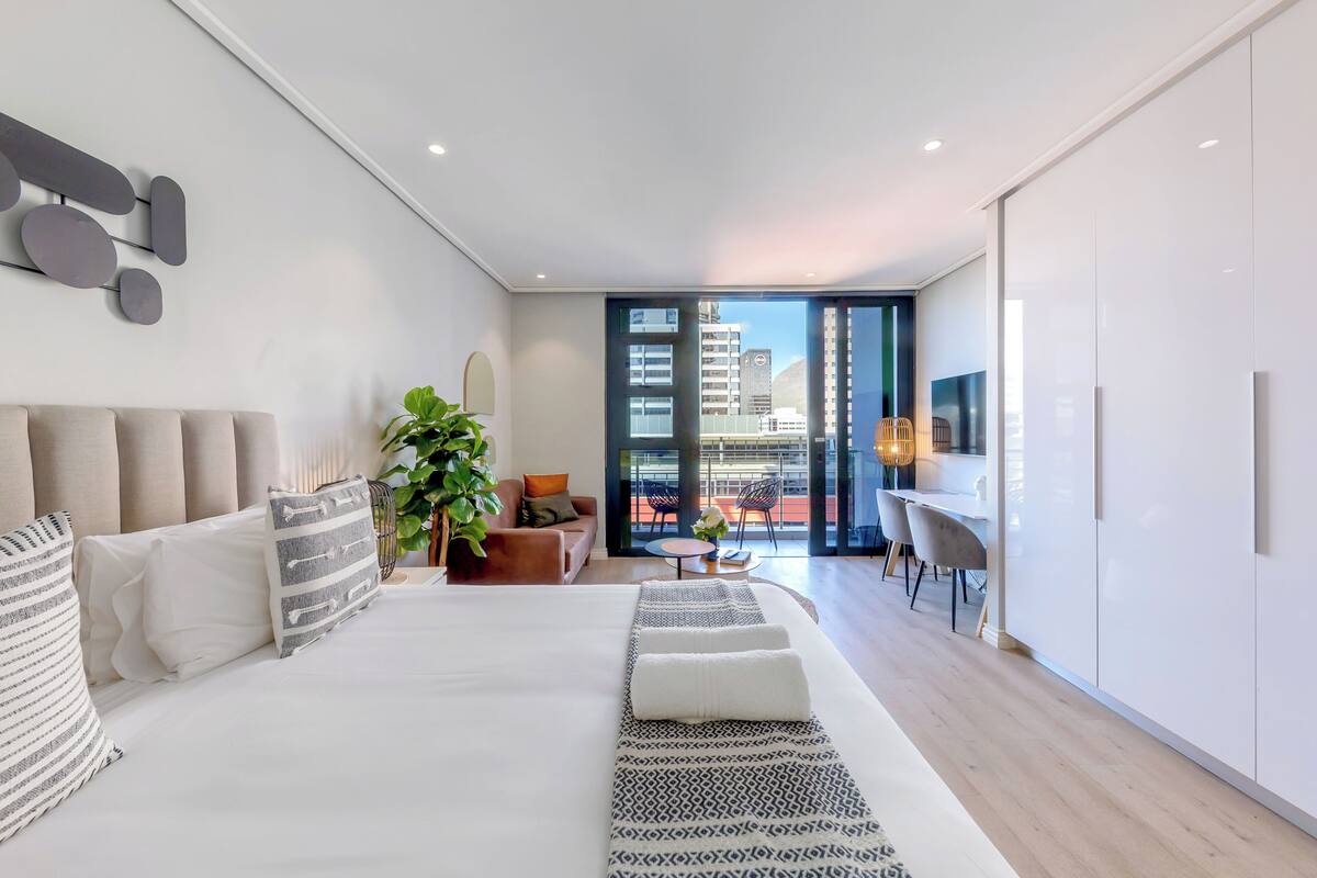 Une chambre d’hôtel moderne dotée d’un grand lit, d’un coin repas et offrant une vue sur la ville.