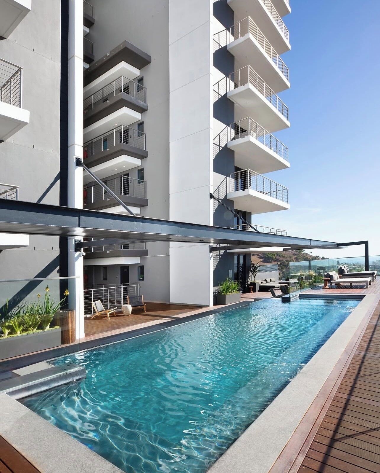 A modern building with a rooftop pool, outdoor seating, and a clear view of the landscape.