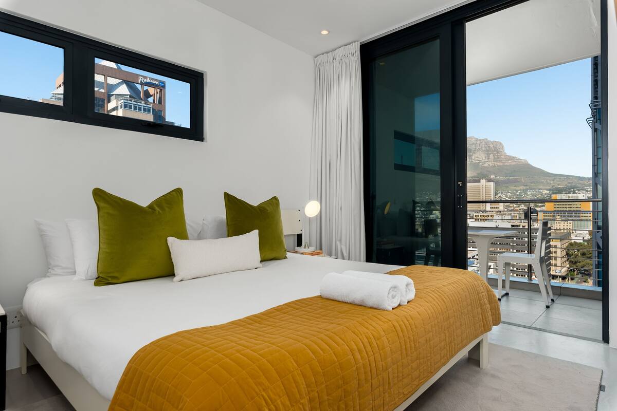 Une chambre d’hôtel moderne avec un grand lit, une vue sur la ville et un balcon.