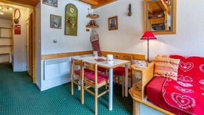 A cozy room with a wooden table, chairs, a red sofa, and a mirror. - 90m from ski slopes, 3rd floor, view mountain, balcony, 27m², Méribel-Mottaret (Méribel - Les Allues)