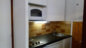 Una cucina compatta con forno a microonde, fornello e lavandino.