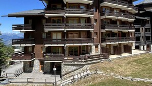 Un hotel a più piani con balconi, fondamenta in pietra e vista sulle montagne.