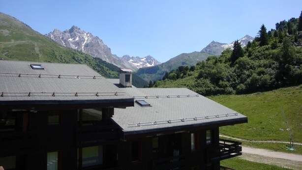 Un edificio con tetto spiovente, diverse finestre e vista sulle montagne innevate.
