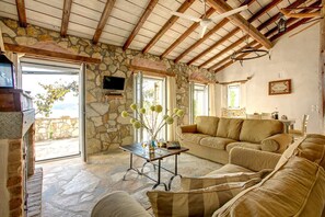 A cozy living room with stone walls, a stone floor, a sofa, a coffee table, and a fireplace.