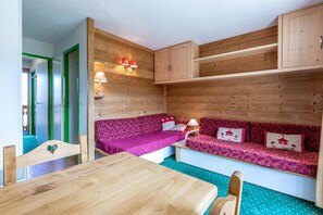A compact room with a wooden wall, a wooden table, and two sofas with patterned upholstery.