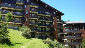 Un hôtel à plusieurs étages doté de balcons, d’une pente herbeuse et surplombant un ciel bleu azur.