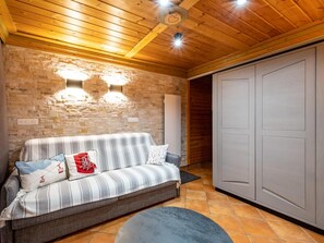 A cozy room with a sofa, a stone wall, and a wardrobe. - 130m from ski slopes, 1st floor, view resort, balcony, ski locker, 44m², Méribel-Mottaret (Méribel - Les Allues)