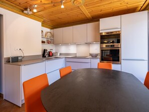 A modern kitchen with white cabinets, a central island with seating, and built-in appliances.