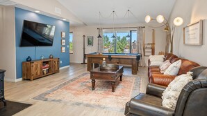 A living room with a pool table, leather sofa, and a TV mounted on the wall. - Pool Table + Firepit + BBQ | Eastside Paso Wine Country | Casa Merlot (Paso Robles)