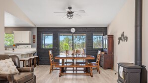 A spacious living room with a wooden dining table, leather sofa, and a wood-burning stove. - Pool Table + Firepit + BBQ | Eastside Paso Wine Country | Casa Merlot (Paso Robles)