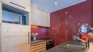 Eine moderne Küche mit Holzausbau, einer roten Küchenrückwand, einer Edelstahl-Spüle und einem eingebauten Backofen.