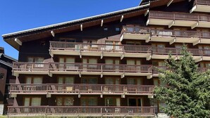 Ein mehrgeschossiges Hotel mit Balkonen, einer Holzfassade und blauem Himmel.