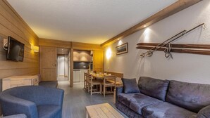 A cozy living room with a sofa, armchair, and wooden coffee table. A dining area with a table and chairs is visible in the background. - 80m from ski lifts, 4th floor, balcony, ski locker, 46m², Méribel-Mottaret (Méribel - Les Allues)