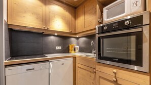 A compact kitchen with wooden cabinets, a built-in dishwasher, a microwave, and an oven. - 80m from ski lifts, 4th floor, balcony, ski locker, 46m², Méribel-Mottaret (Méribel - Les Allues)