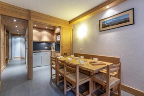 Una mesa de comedor de madera con sillas, una cocina con armarios de madera y un cuadro en la pared.