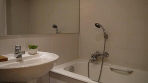Ein Badezimmer mit einem weißen Waschbecken, einer kleinen Topfpflanze und einer Badewanne mit Duschkopf.
