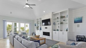 Una sala de estar moderna con un sofá gris, una mesa de centro de madera y un televisor montado en una pared de ladrillo blanco.