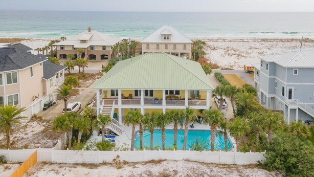 Una propiedad frente a la playa con varias casas, una piscina y vista al mar.