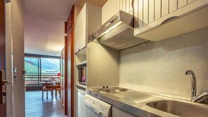 A modern kitchen with stainless steel appliances, a built-in oven, and a large window overlooking a scenic landscape. - 20m from ski slopes, 3rd floor, view mountain, balcony, ski locker, 24m², Méribel-Mottaret (Méribel - Les Allues)