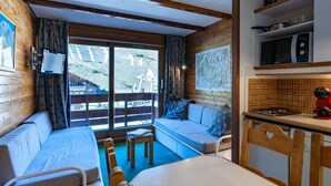 Interior acogedor de una cabaña con sofá, mesa de comedor y zona de cocina.